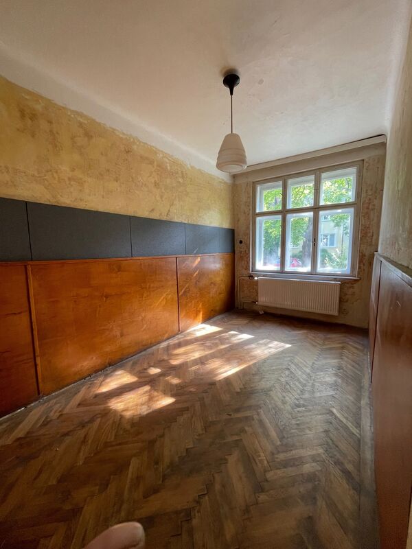 Místnost s dřevěným obložením, zlatou texturou stěny a parketovou podlahou