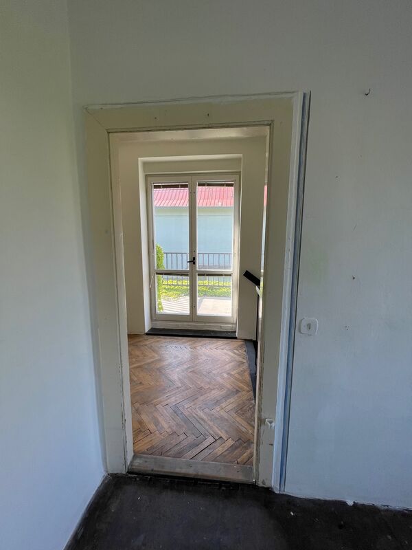 Místnost s balkónovými dveřmi a parketovou podlahou